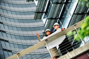 Two people standing on a balcony with a building in the background